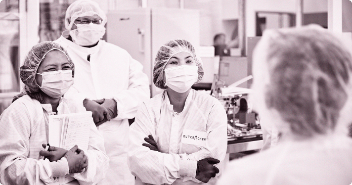 4 team members in lap coats having a discussion in a lab