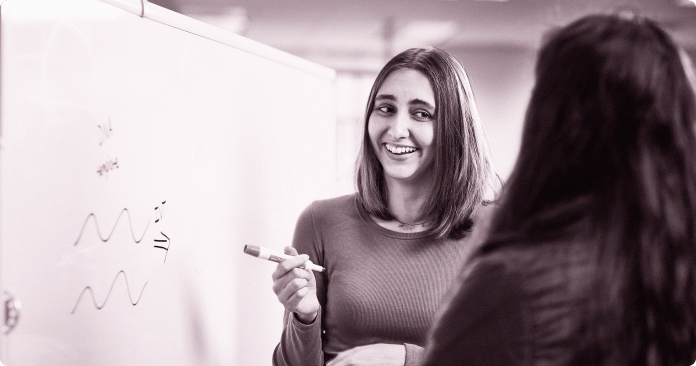 2 team members having a discussion in front of a white board