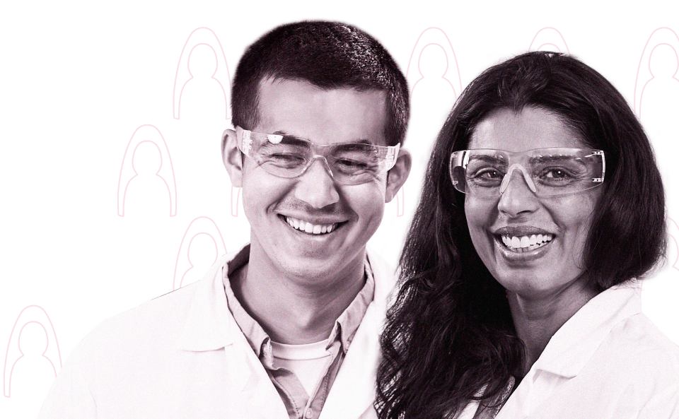 Two team members smiling with lab coats and eye protection gear